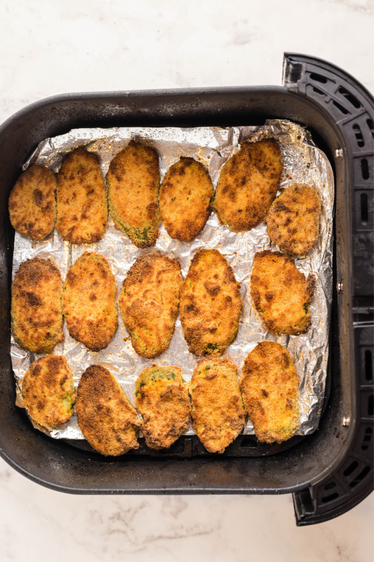 Golden, crispy fried pickles in the air fryer basket after cooking
