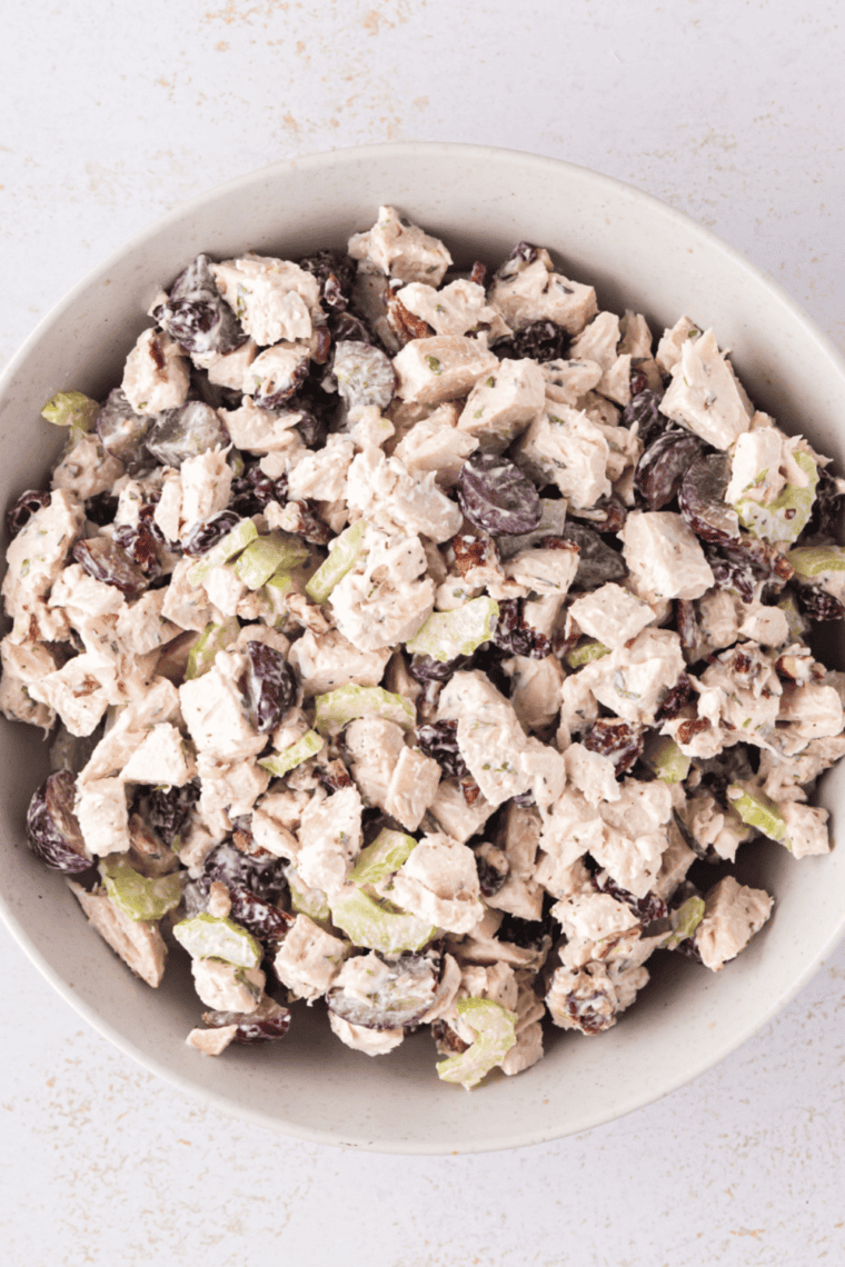 Creamy chicken salad mixture spread evenly in a baking dish and topped with shredded cheddar