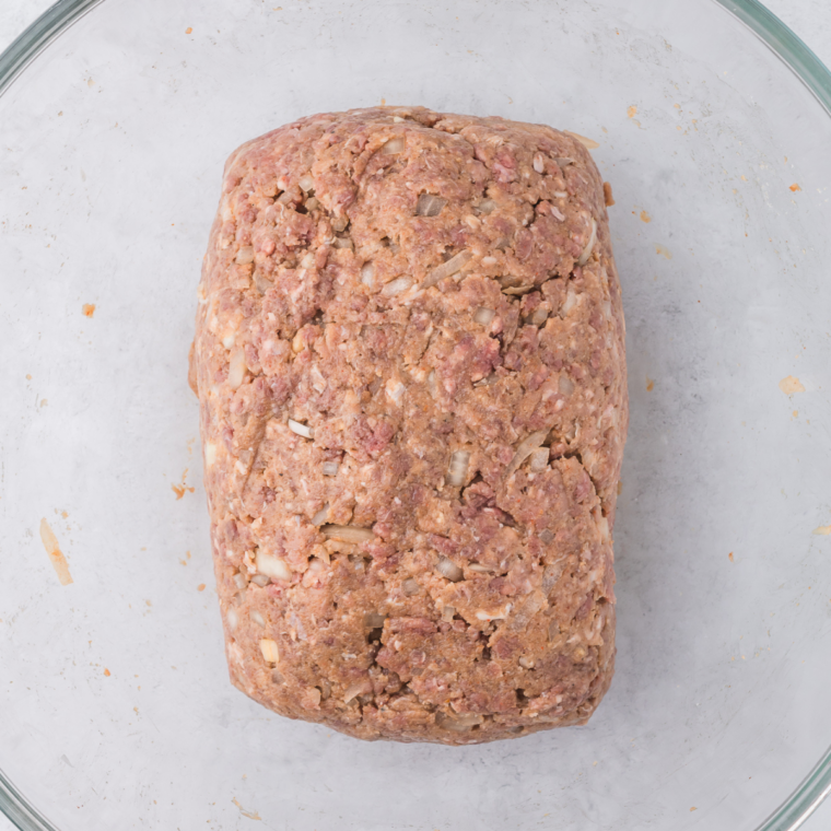 Raw meatloaf mixture pressed into a greased loaf pan before baking
