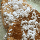 Homemade Buc-ee's Beaver Tail recipe with icing drizzle on parchment paper
