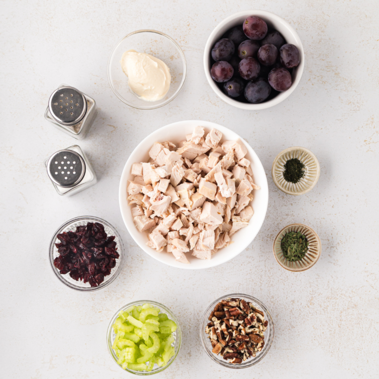 Ingredients for Buc-ee's chicken salad recipe, including rotisserie chicken, mayonnaise, sour cream, lemon, honey, dried cranberries, pecans, celery, and green onions