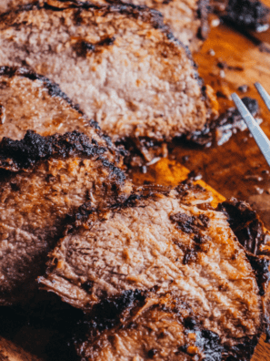 Copycat Buc-ee's brisket sliced on a wooden cutting board with a dark peppery bark
