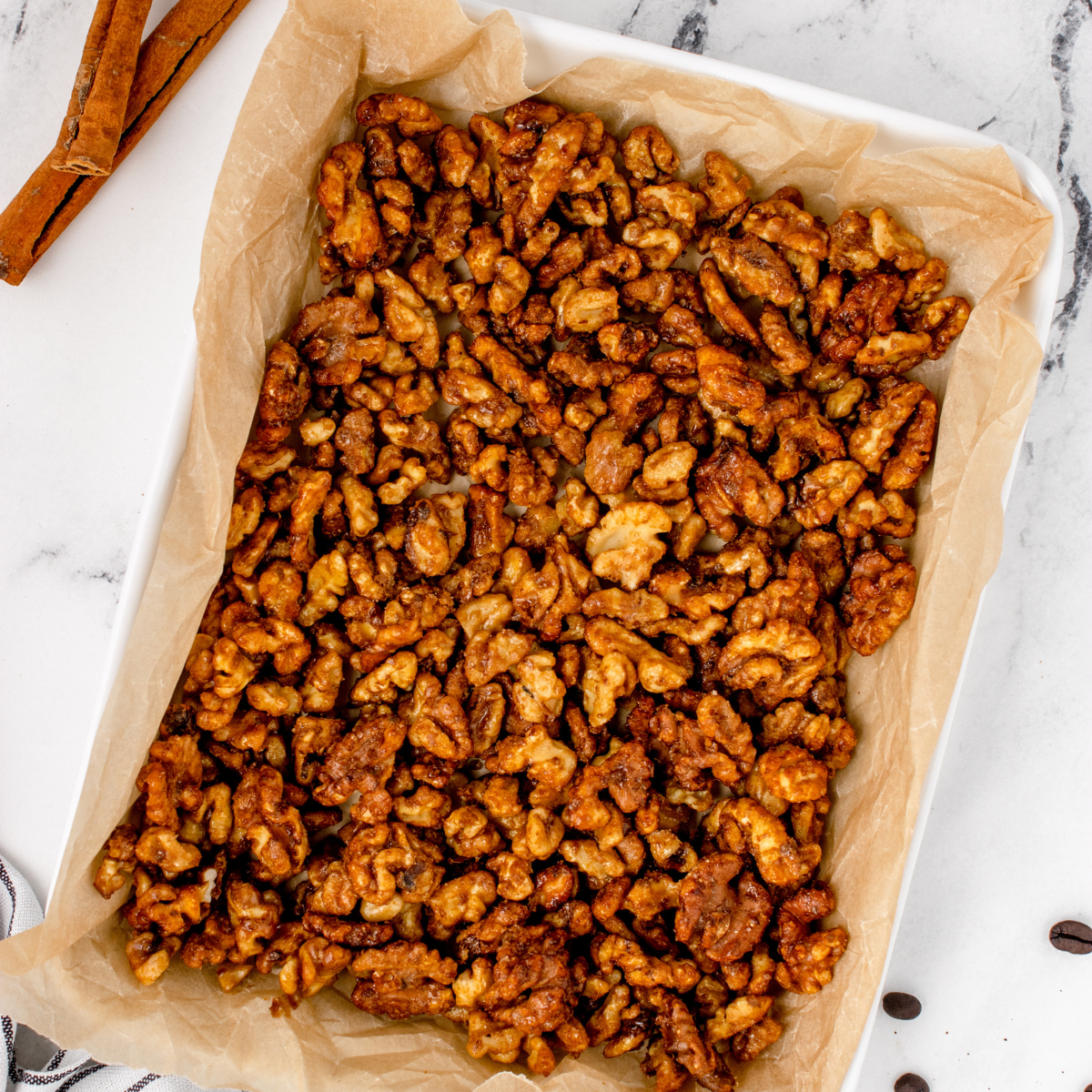 Copycat Buc-ee's candied almonds and cashews with a cinnamon sugar glaze on a parchment-lined baking sheet