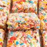 Stack of three thick copycat Buc-ee's Fruity Pebbles rice crispy treats with a bite taken from the top square
