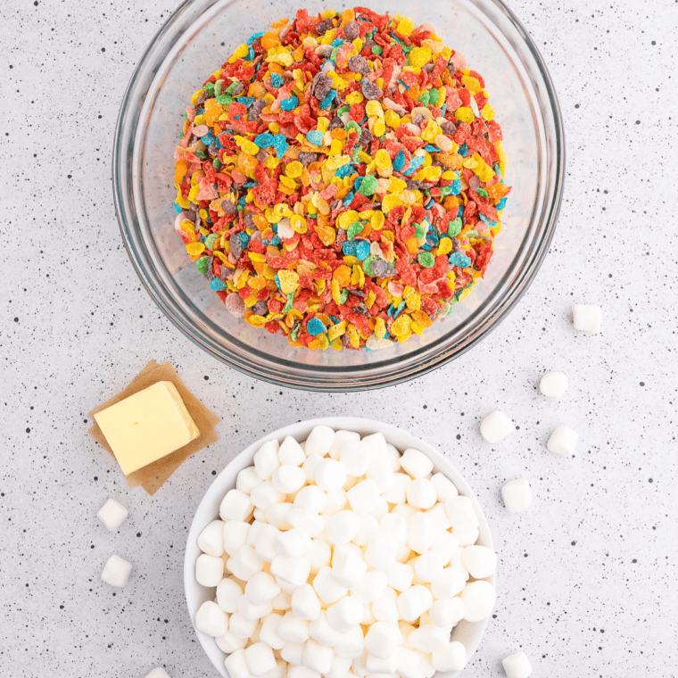 Ingredients flat lay: Butter, mini marshmallows, vanilla, Fruity Pebbles, and Rice Krispies laid out for copycat Buc-ee's treats