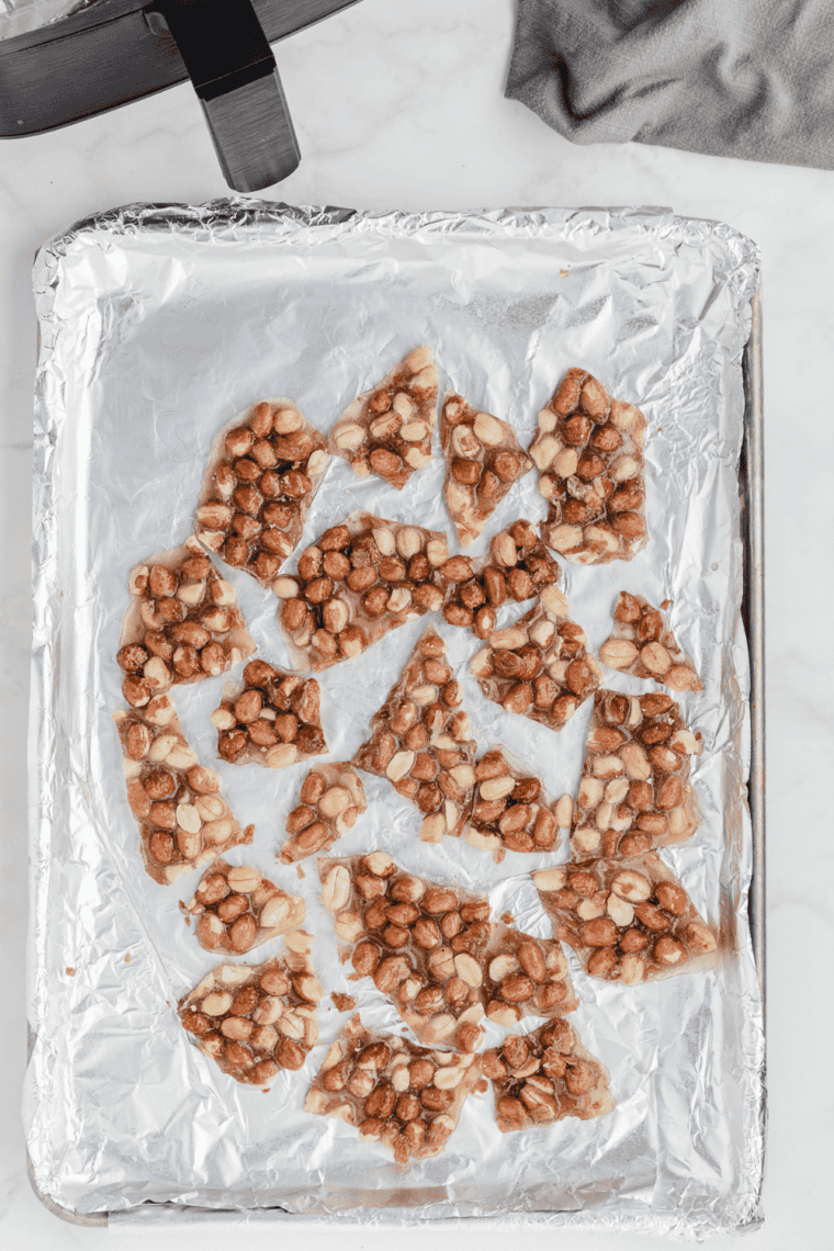 Copycat Buc-ee's pecan pralines recipe card image with pralines on foil baking tray.