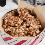 Copycat Buc-ee's pecan pralines stacked on parchment paper with pecan halves scattered around