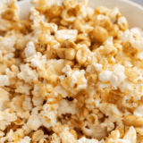 Copycat Buc-ee's popcorn kettle corn piled high in a large white bowl with loose kernels scattered on the counter