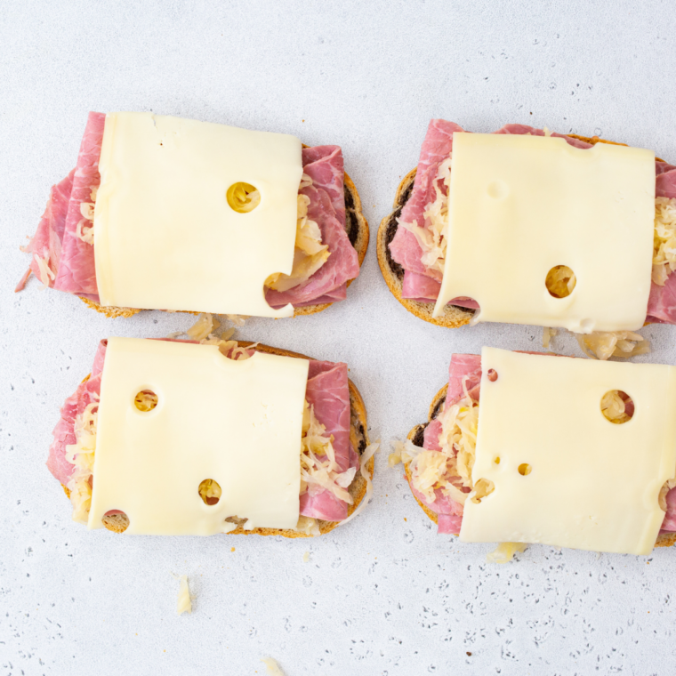 Assembling a Reuben with Swiss, corned beef, sauerkraut, and Thousand Island on buttered rye