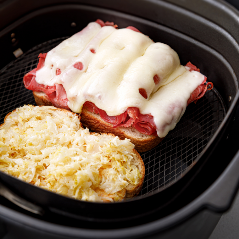 Reuben sandwiches held with toothpicks in an air fryer basket