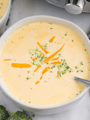 Copycat Denny's broccoli cheese soup in a white bowl topped with shredded cheddar