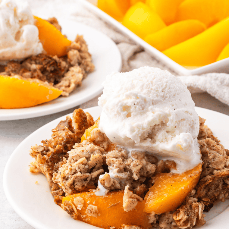 Copycat Kashi GoLean Crunch granola clusters in a white bowl with milk and sliced peaches.