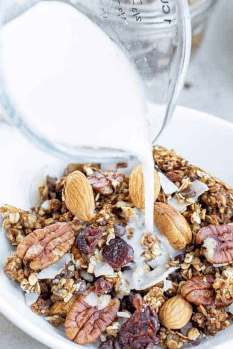 Copycat Kashi GoLean Crunch granola clusters in a white bowl with milk and sliced almonds