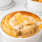 Copycat Perkins chicken pot pie in a crock with golden flaky puff pastry crust broken open to show creamy chicken and vegetable filling