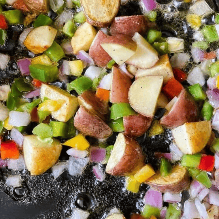 Sautéing diced onion, celery, carrots, and potato in butter in a skillet for Perkins chicken pot pie filling