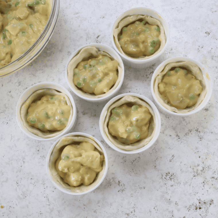 Creamy chicken pot pie filling divided into four oven-safe ramekins