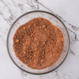 Bowl of copycat Steak 'n Shake Cajun seasoning with a spoon and paprika-red spice blend