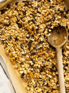Cracker Barrel granola recipe with golden honey oat clusters, sliced almonds, and dried cranberries on a baking sheet
