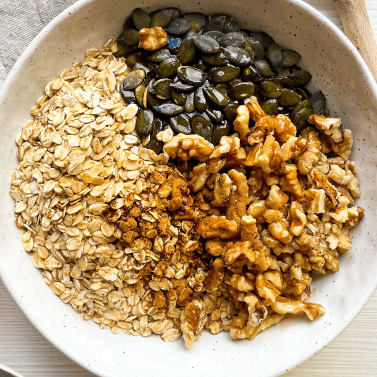 Granola mixture pressed into an even layer on a parchment-lined baking sheet before baking