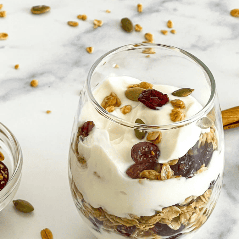 Finished Cracker Barrel granola recipe in a glass jar with a scoop of honey almond clusters beside it