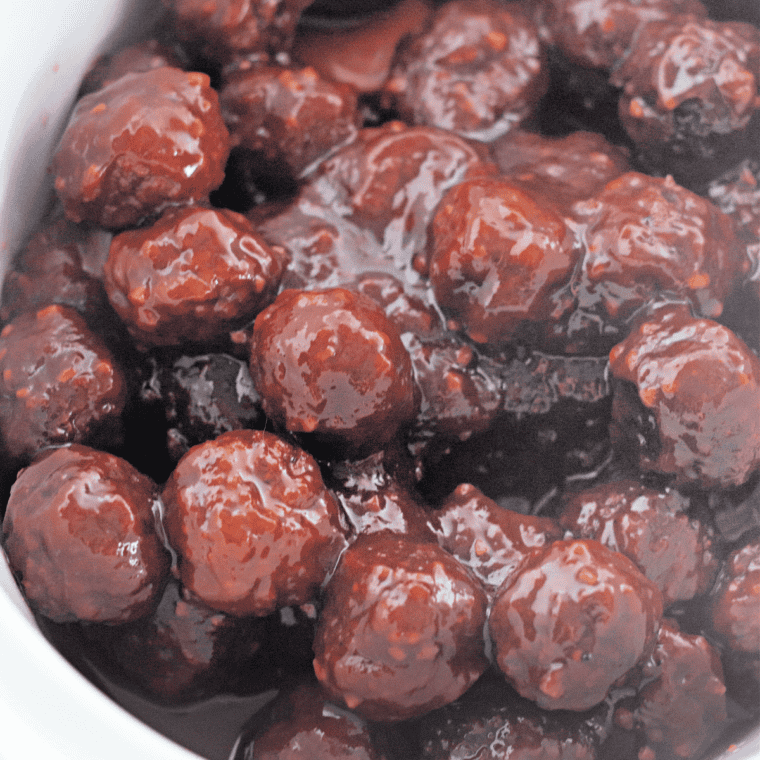 Cocktail meatball on a toothpick coated in sticky cranberry chili sauce