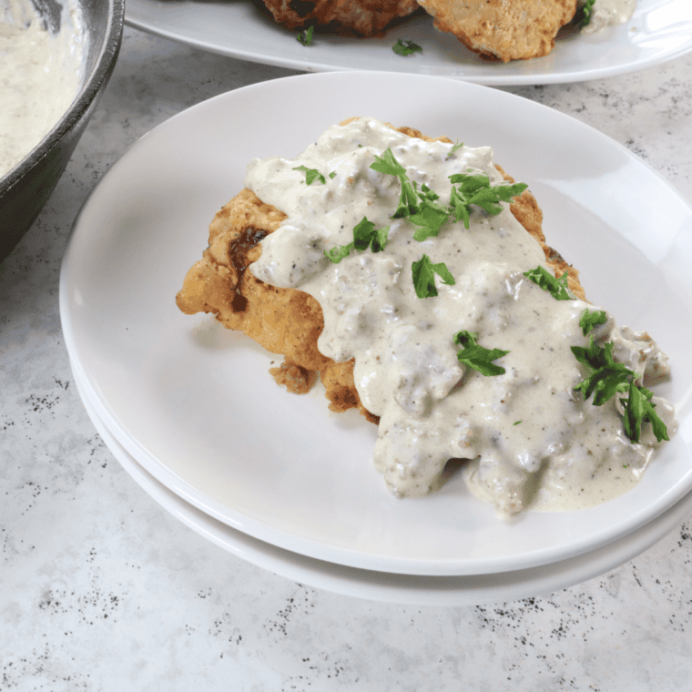 Close-up of crispy Denny's country fried steak with creamy country gravy dripping down the sides
