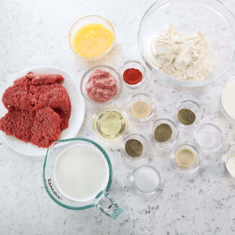 Ingredients for Denny's country fried steak recipe: cube steaks, flour, buttermilk, eggs, seasonings, butter, and milk arranged in bowls