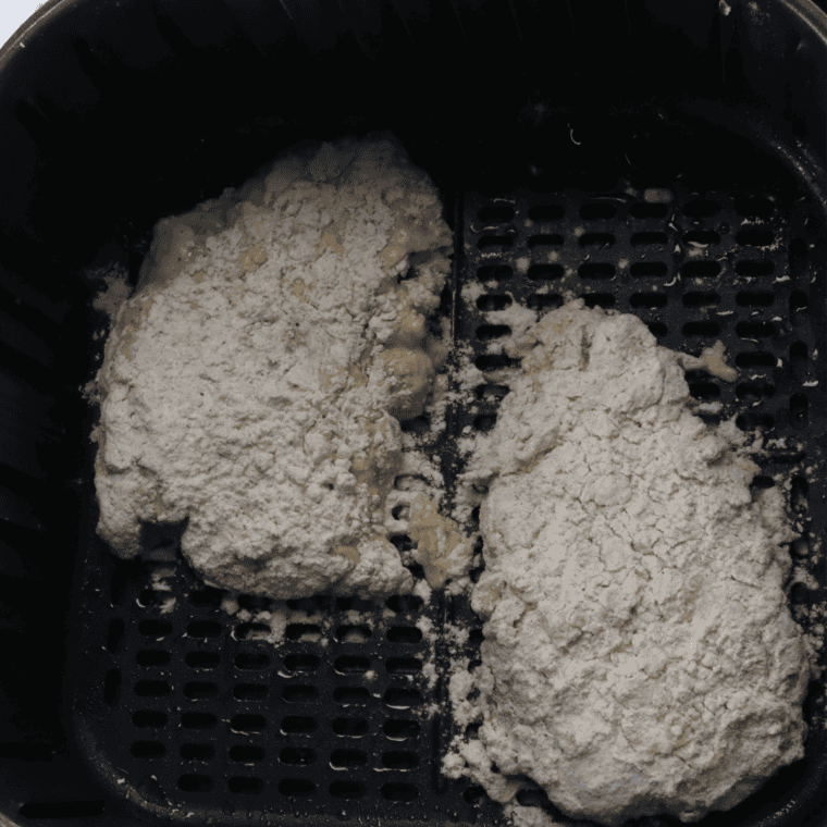 Double-breaded cube steaks resting on a wire rack before going into the air fryer