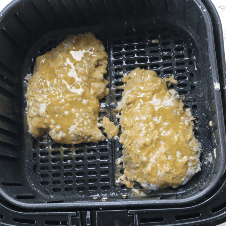 Empty air fryer basket sprayed with oil and preheating to 400°F