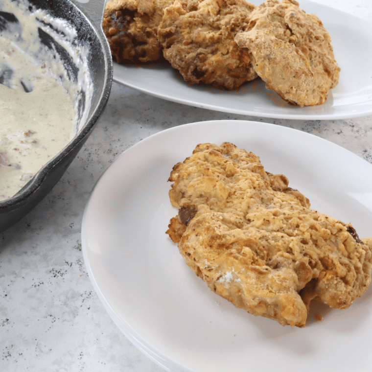 Golden crispy country fried steaks cooking in an air fryer basket after flipping