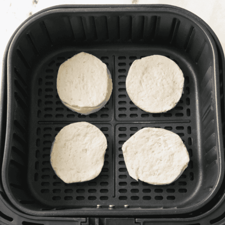 Biscuits arranged in a single layer in an air fryer basket for Denny's sausage gravy and biscuits