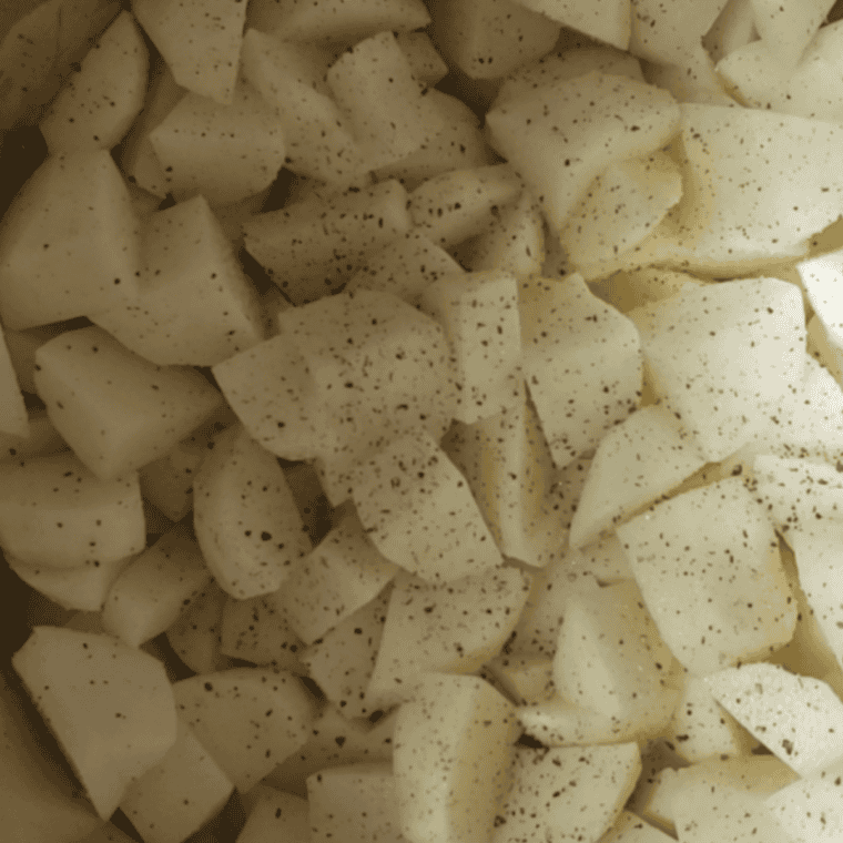 Red-skinned potatoes hand-mashed with butter in a pot, showing a rustic texture with visible potato skin