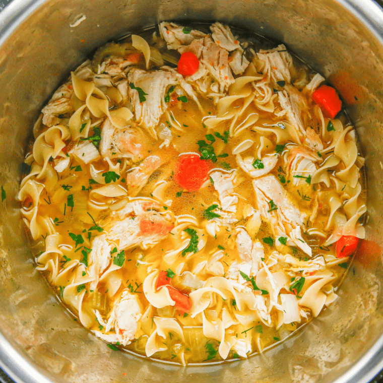 Egg noodles simmering on sauté mode in an Instant Pot to finish chicken noodle soup