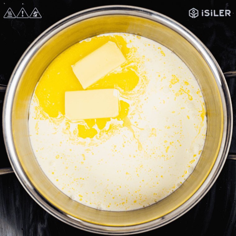 Heavy cream and cubed cream cheese being whisked into a skillet until smooth