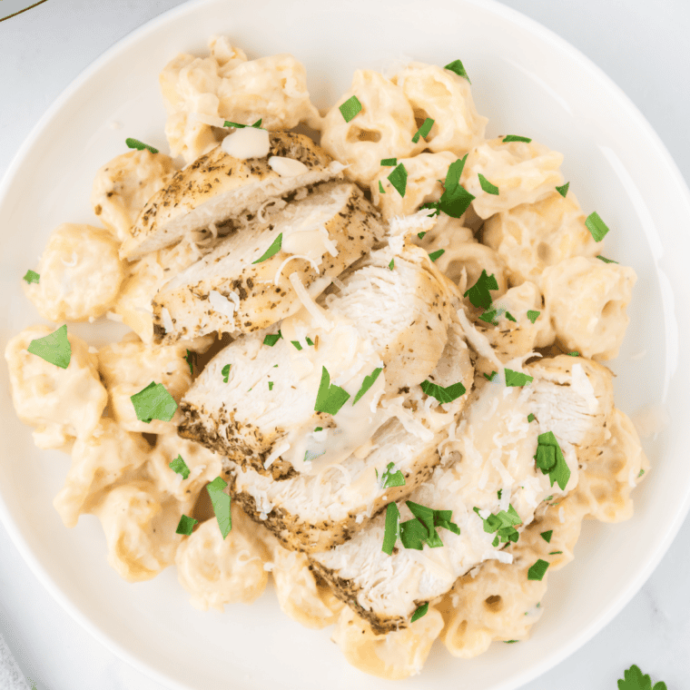Fettuccine Alfredo plated in a white bowl topped with grated Parmesan and fresh parsley