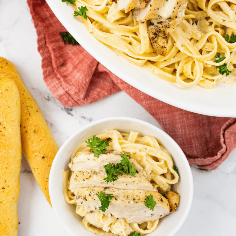 Creamy copycat Fazoli's fettuccine Alfredo in a white bowl topped with grated Parmesan and fresh parsley