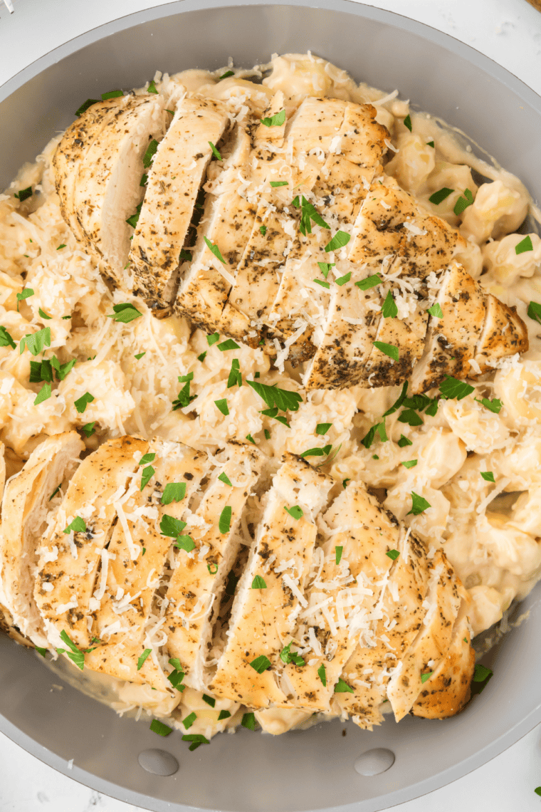 Copycat Fazoli's chicken fettuccine Alfredo topped with sliced grilled Italian-seasoned chicken and grated Parmesan