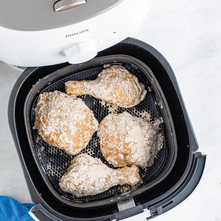 Chicken pieces frying in a cast iron skillet of hot oil until golden brown