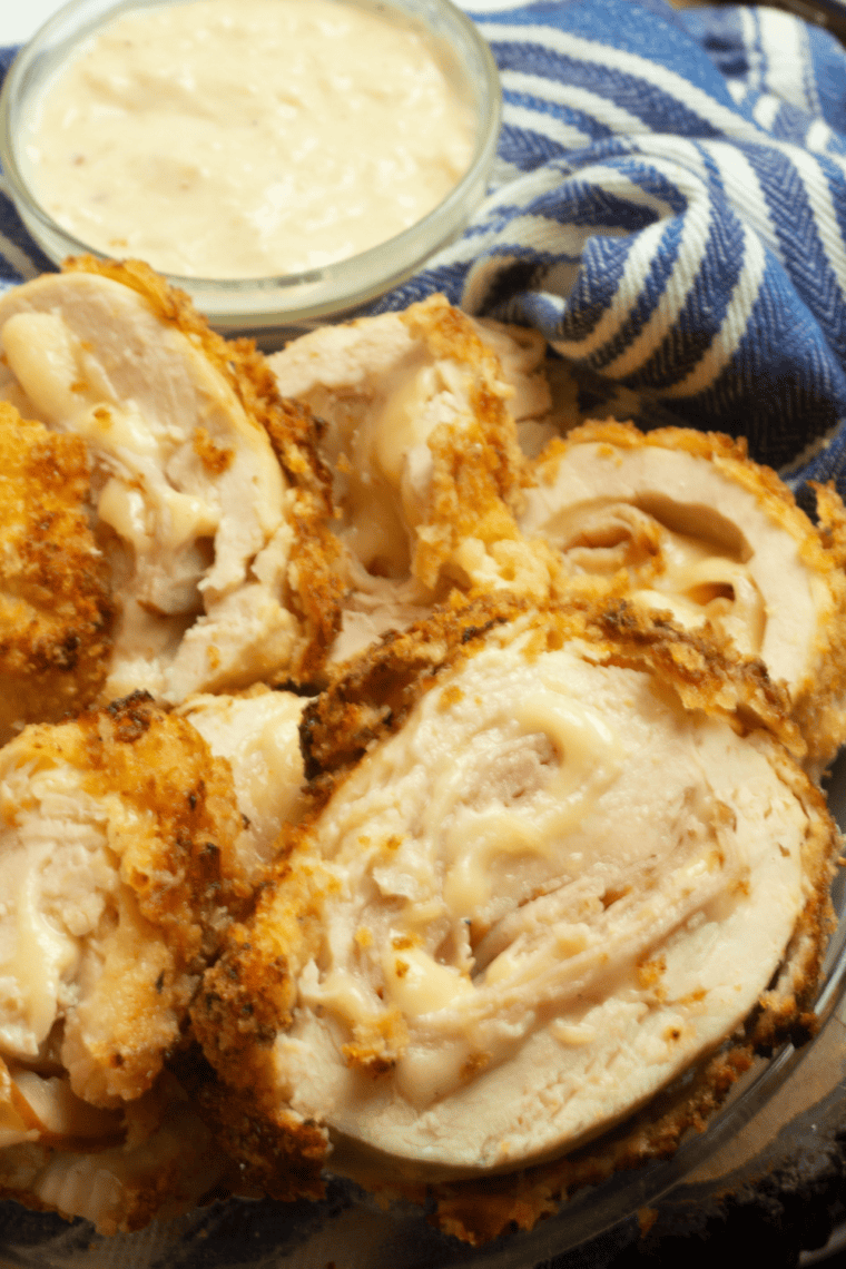 Breaded chicken cordon bleu rolls searing in olive oil in a skillet until golden