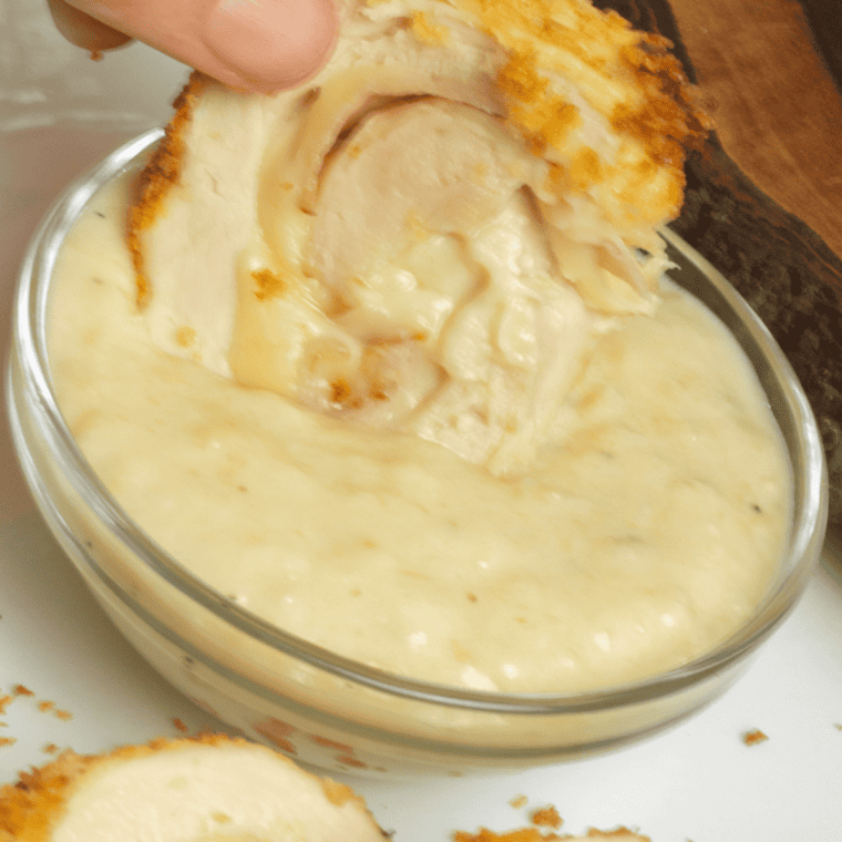 Sliced chicken cordon bleu plated with mashed potatoes, green beans, and Dijon sauce