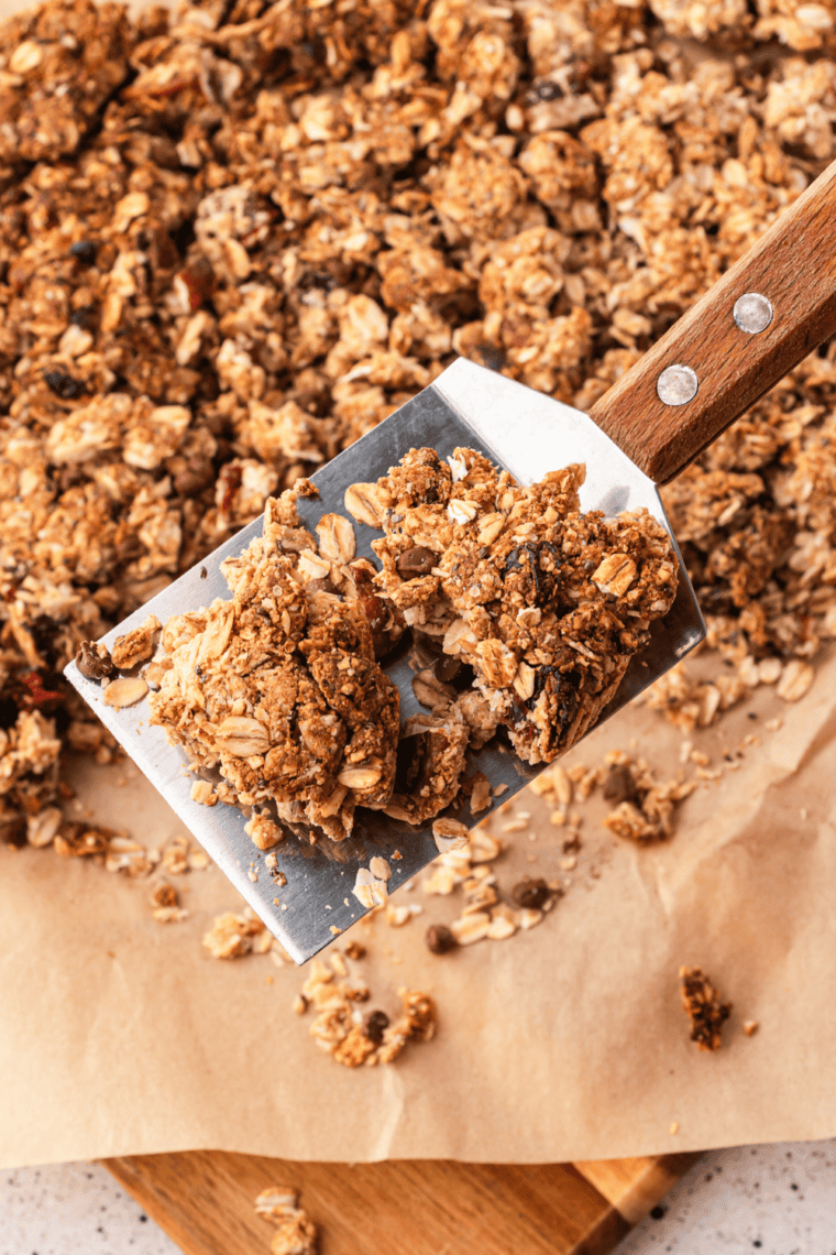 Hands breaking cooled homemade protein granola into large crunchy clusters