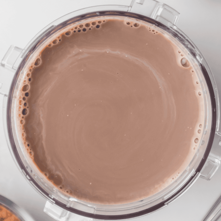 Milk chocolate ice cream base poured into a Ninja Creami pint container below the max fill line and ready to freeze