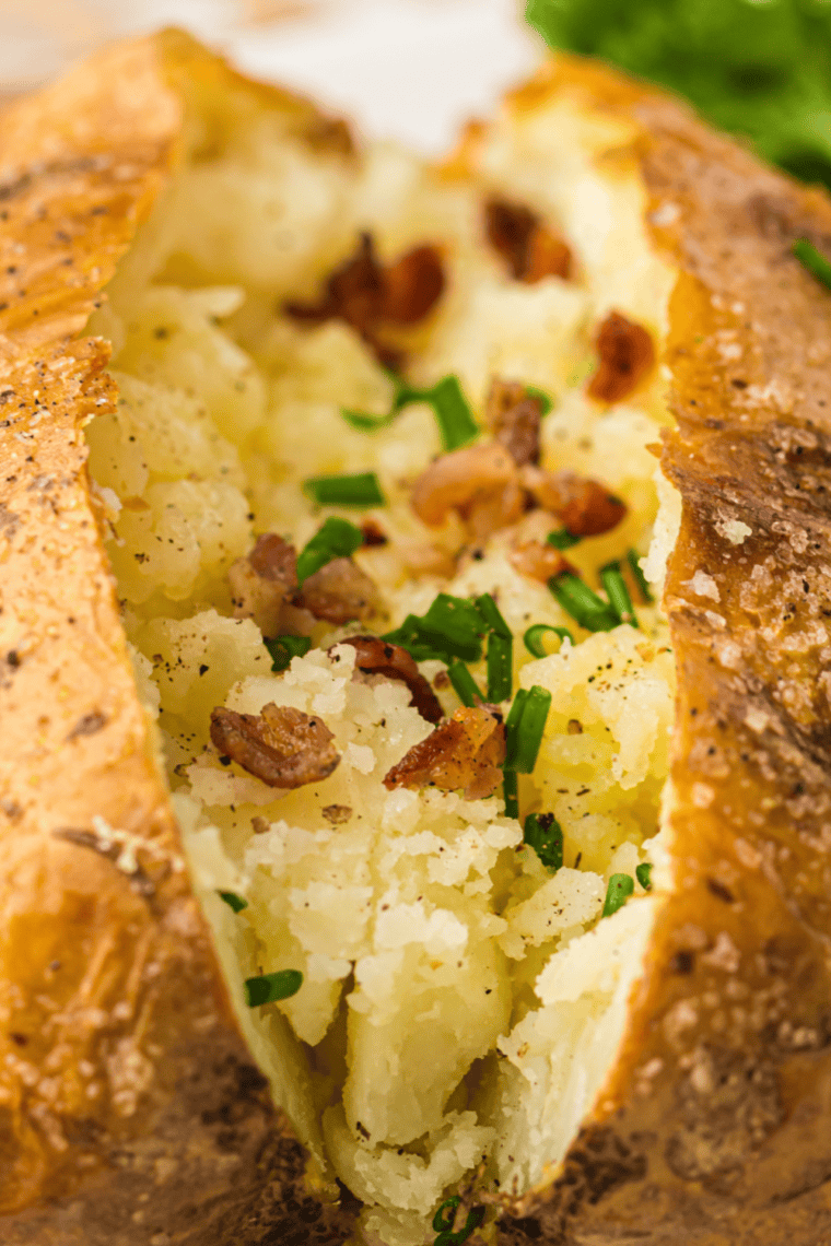Ninja Crispi baked potato with crispy skin split open and topped with butter
