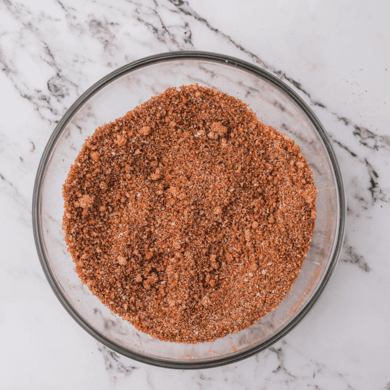 Homemade Omaha steak seasoning in a glass jar with dried garlic, onion, and orange peel