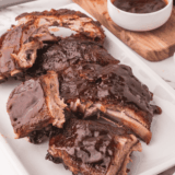 Copycat Outback baby back ribs glazed with sticky BBQ sauce on a wooden cutting board
