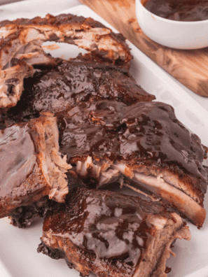 Copycat Outback baby back ribs glazed with sticky BBQ sauce on a wooden cutting board