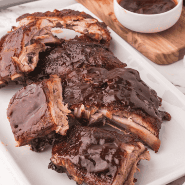 Copycat Outback baby back ribs glazed with sticky BBQ sauce on a wooden cutting board