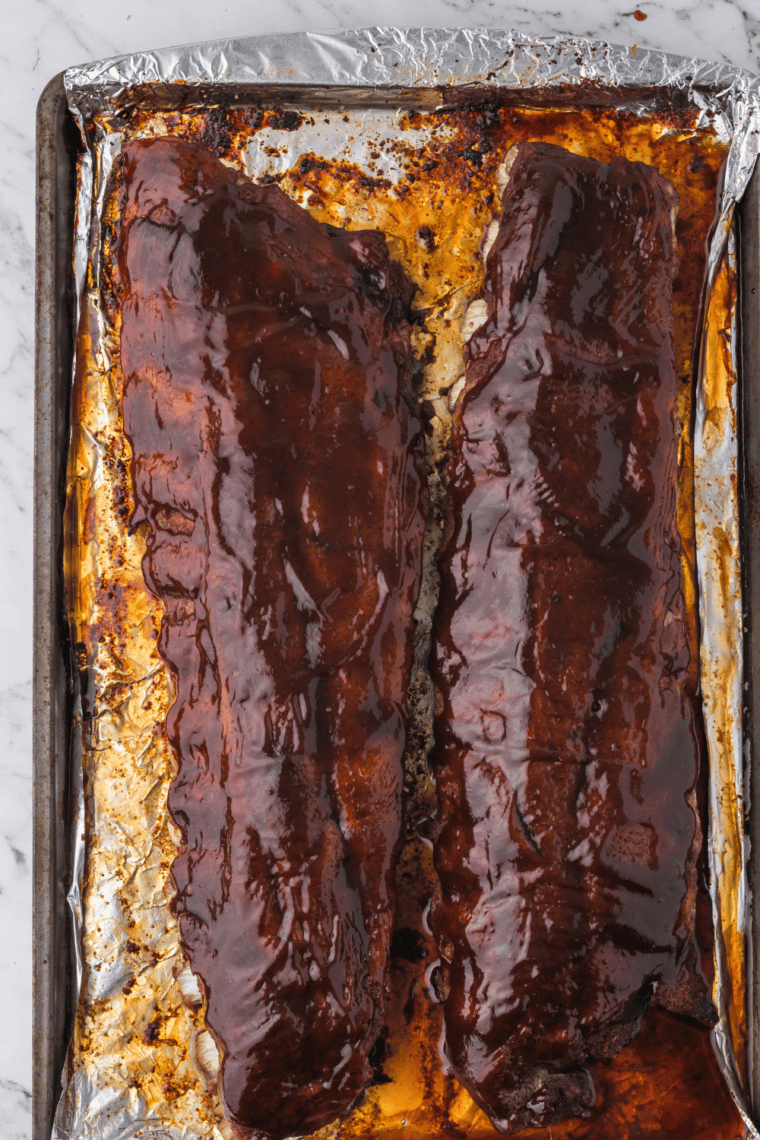 Brushing BBQ glaze onto oven-baked baby back ribs before broiling