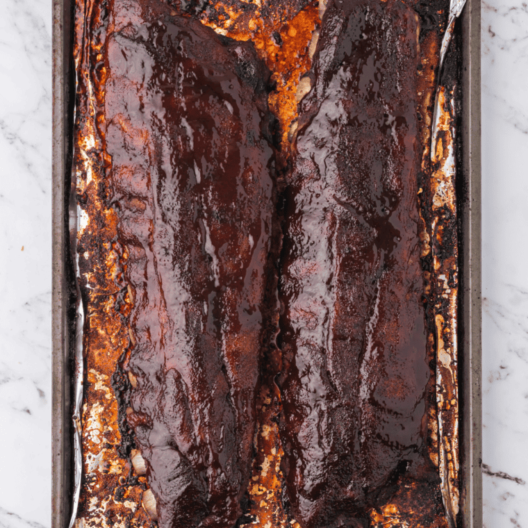 Sliced copycat Outback baby back ribs with caramelized BBQ glaze served with extra sauce