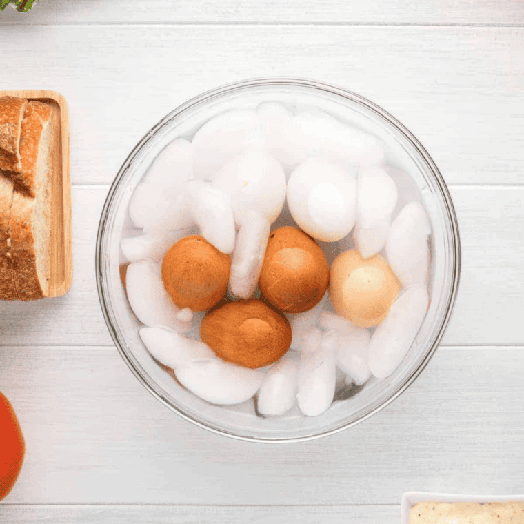 Peeled hard-boiled eggs next to a pile of cracked shells